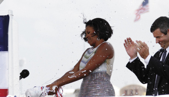 Michelle Obama uses those famous arms to christen a Coast Guard ship. Photo source: New Pittsburgh Courier.